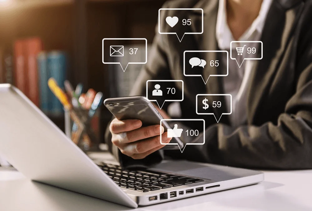 Photo of a phone and laptop with overlaid icons for likes, messages and comments