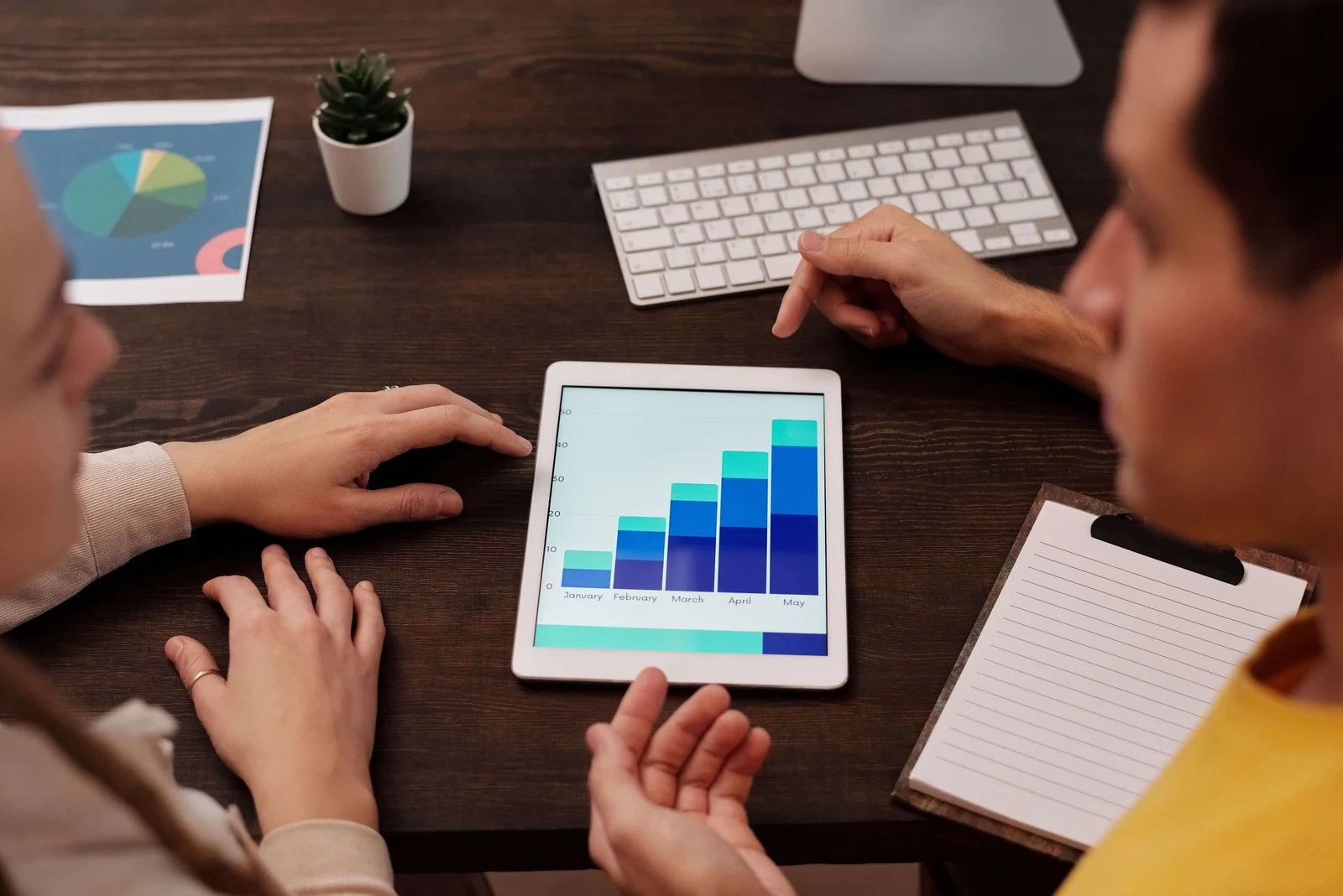 Photo of a discussion at a table with a bar chart on a tablet
